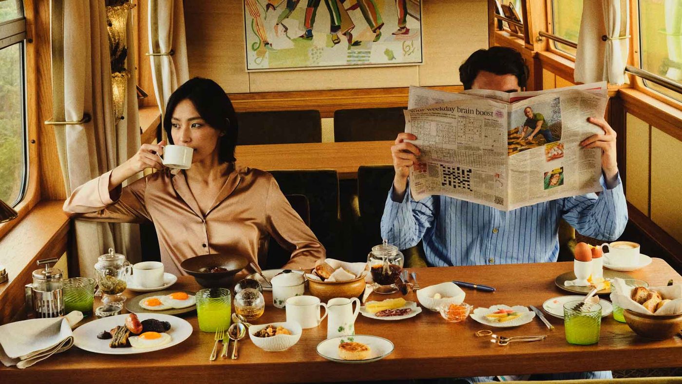 Two guests at breakfast by a window table on the train