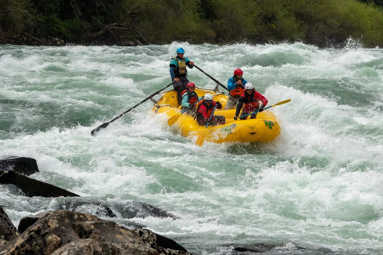 A raft crew paddling through white water between rocks