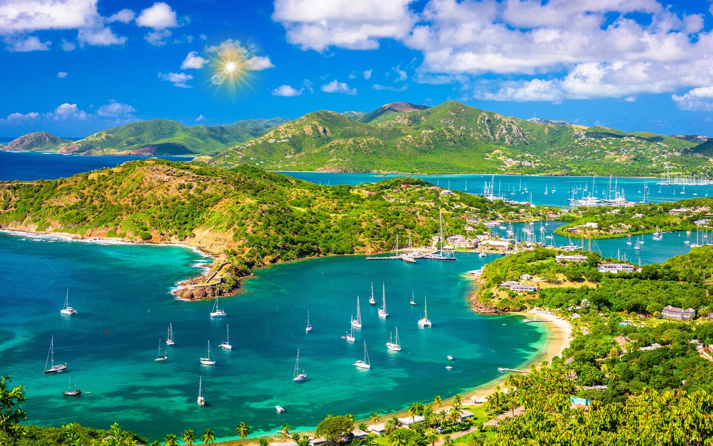 Yachts moored in a green, sheltered harbour seen from a hilltop