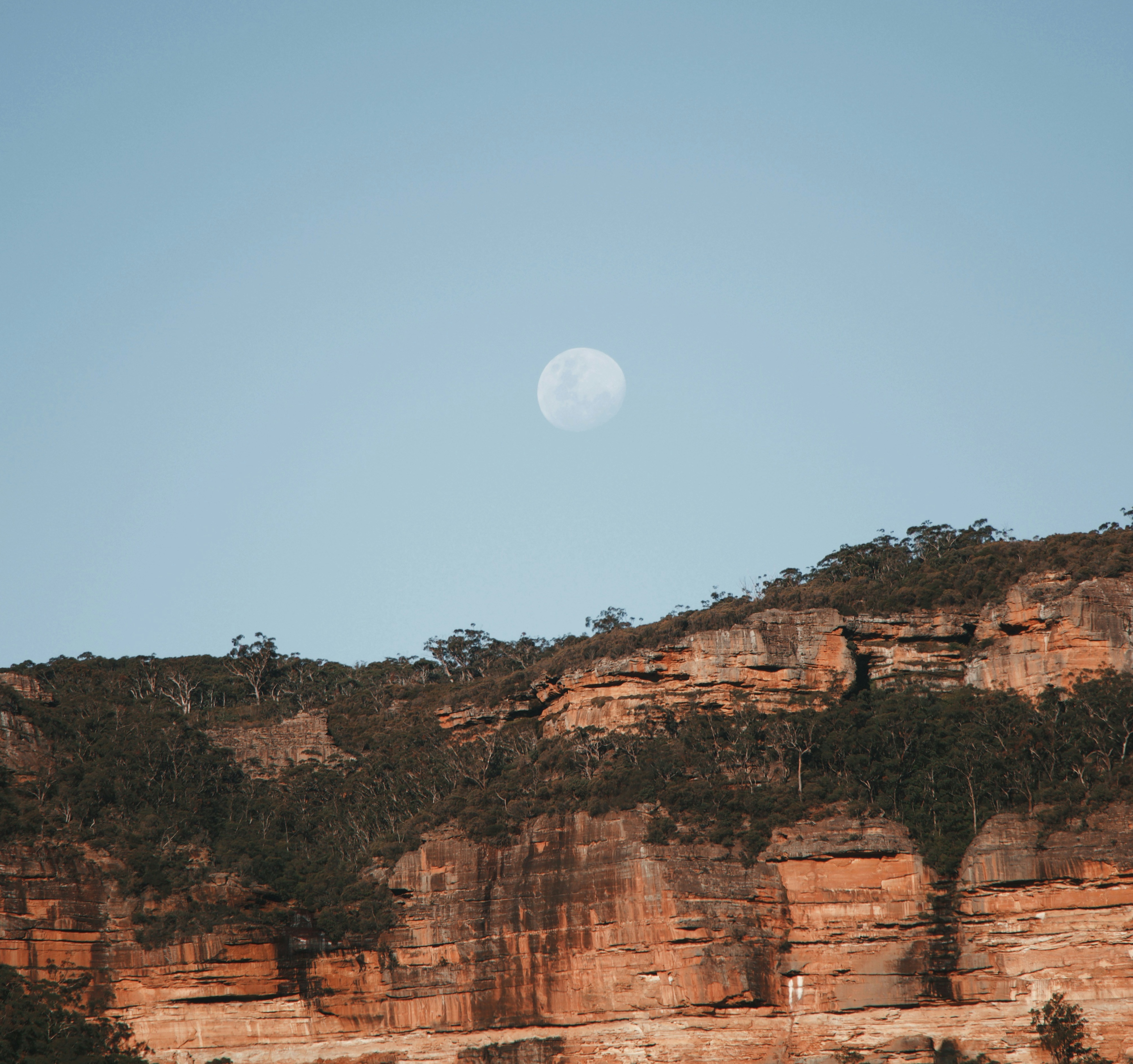 Blue mountains with the moon rising above them.